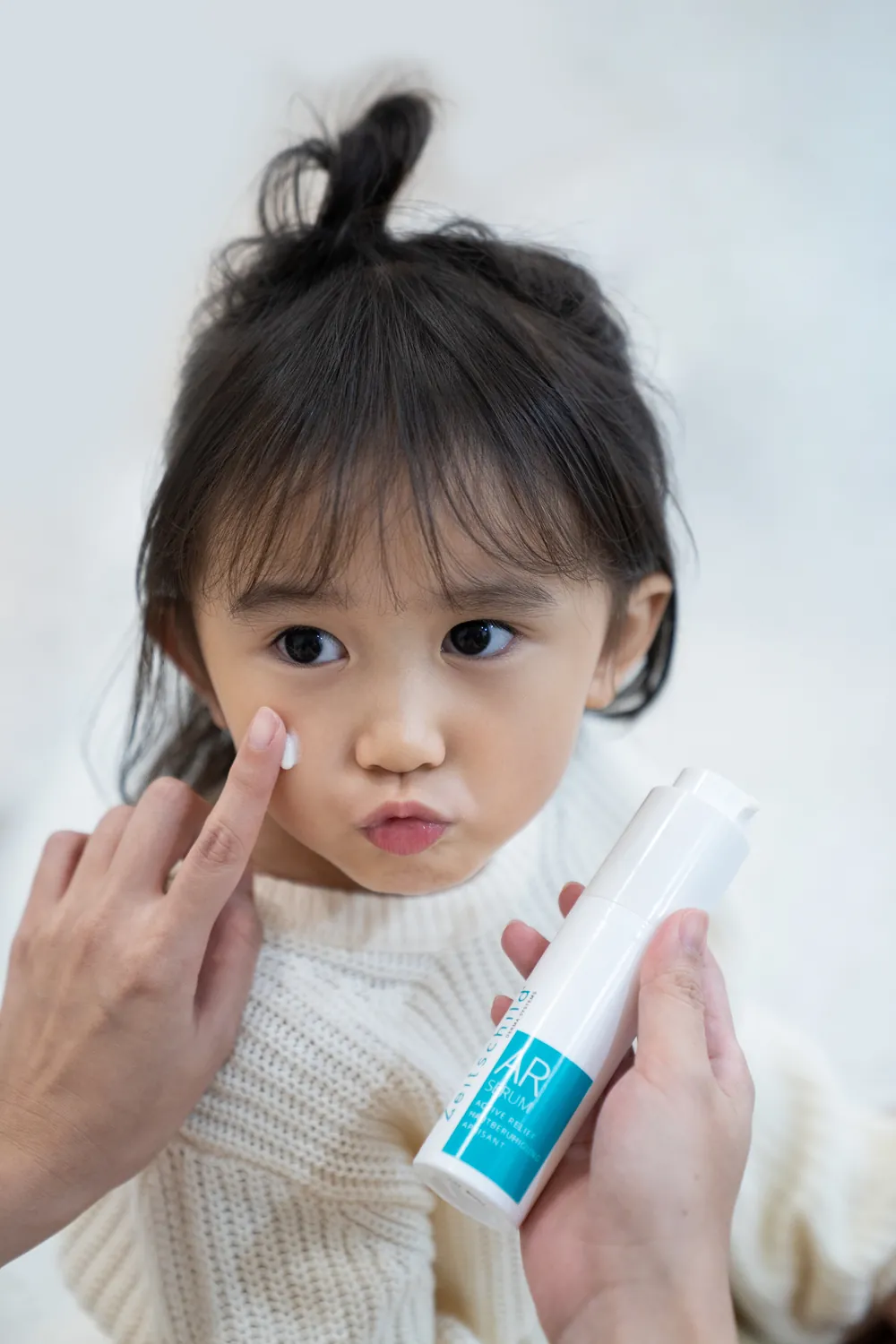 Parent applying Zeitschild AR Serum to a young child's cheek